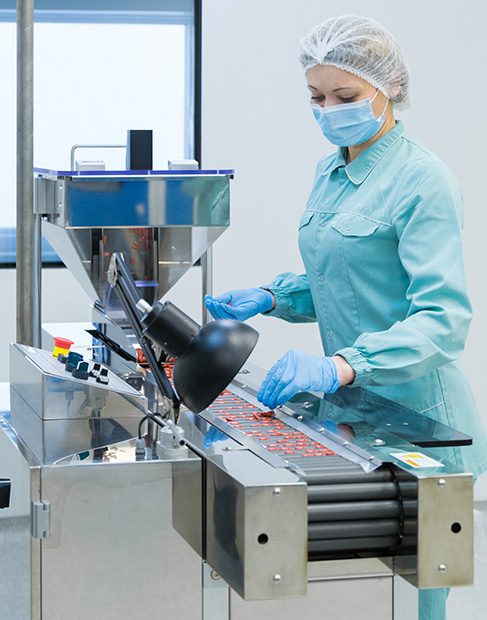 Pharmaceutical technician in sterile environment working on production of pills at pharmacy factory